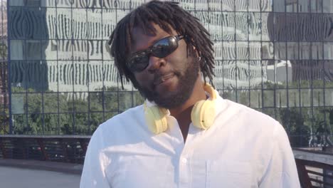 Stylish-black-man-listening-to-music-on-urban-pavement