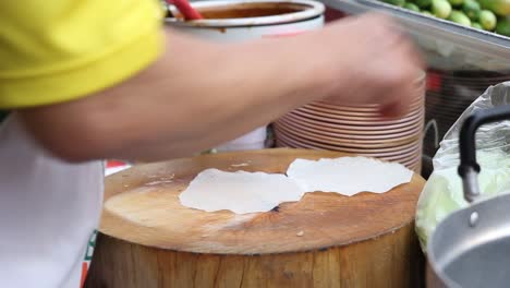 chef separating rice paper and starts preparing asian wraps, close up