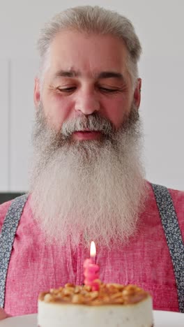 man with beard blowing out candle on birthday cake