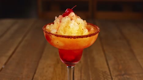 waiter delivering a cocktail with pineapple ice cream, chili powder and vodka on a wooden table