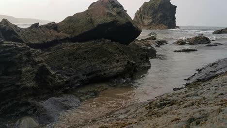 a small stream of water leading out towards the sea in a pebble beach in broad haven, west wales in early evening