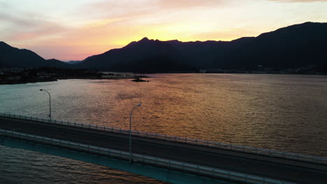 Aerial-view-of-traffic-on-the-Lake-Kawaguchi-bridge-with-silhouette-mountain-background,-in-Japan