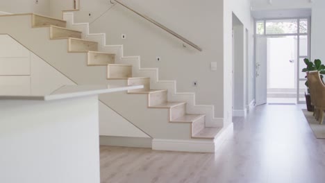 built in furniture in white open plan kitchen, and hallway with stairs in modern house