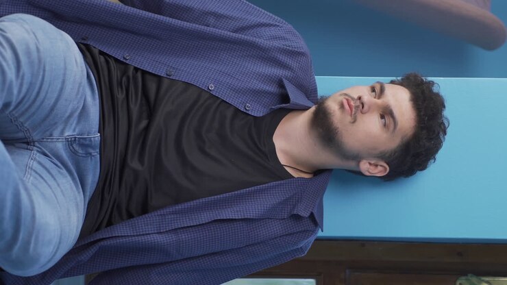 вертикальное видео вдумчивого человека у стены.