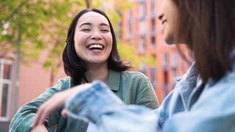 Two-Pretty-Young-Japanese-Girls-Sitting-Outdoors-And-Talking-About-Something-Funny