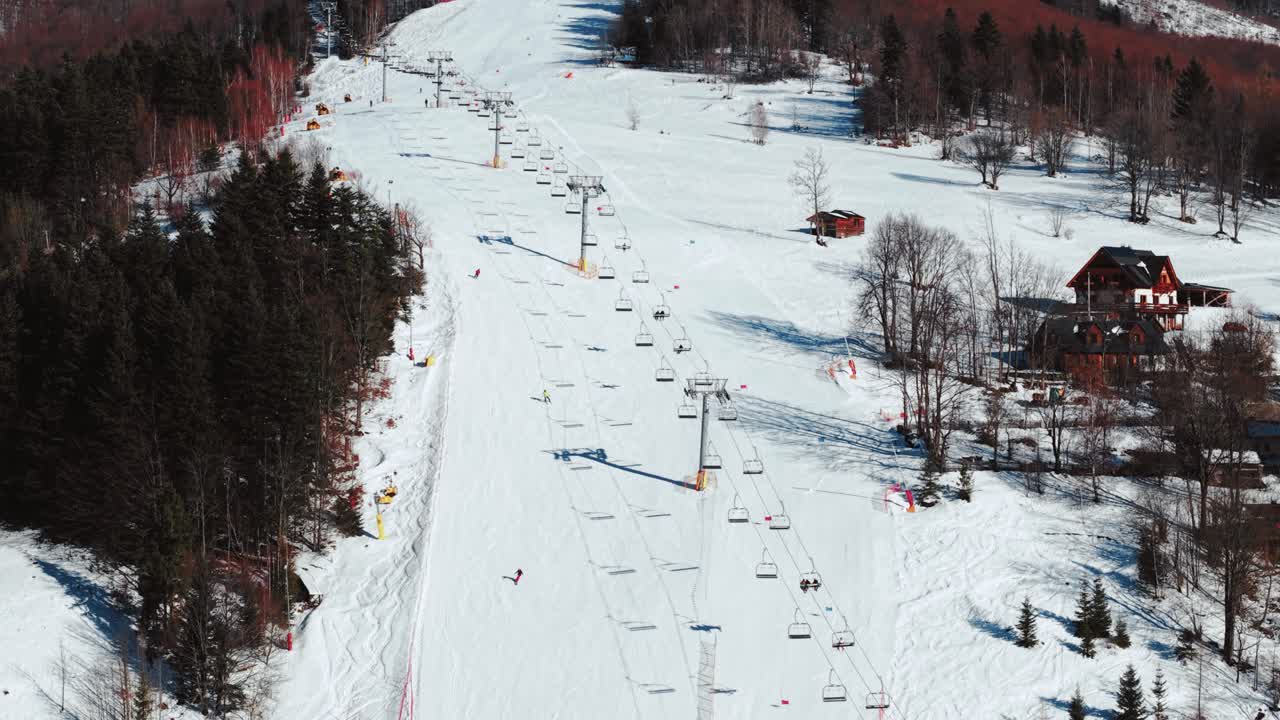 Filmato aereo di una pista di stazione sciistica con sciatori in una limpida giornata invernale