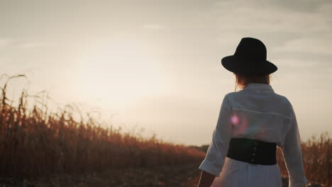 Farmer-in-a-dress-and-hat-walks-in-a-field-of-ripe-corn-4