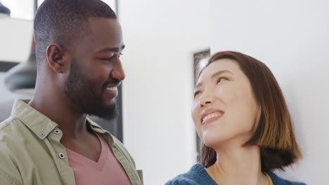 video de una feliz pareja diversa sonriéndose el uno al otro en casa