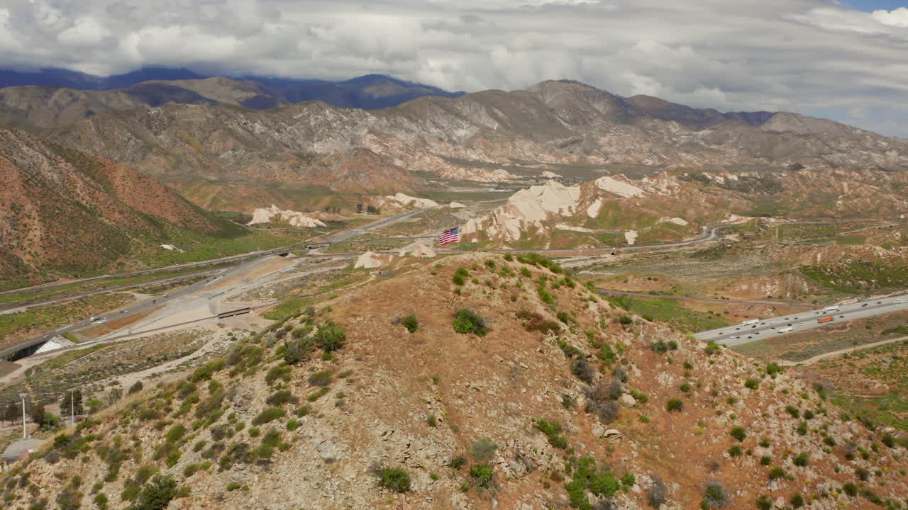 American flag on top of a hill near highway 15 near Phelan, California. Aerial shot