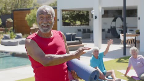 Portrait-of-happy-diverse-senior-man-with-yoga-group-in-sunny-garden,-unaltered,-in-slow-motion