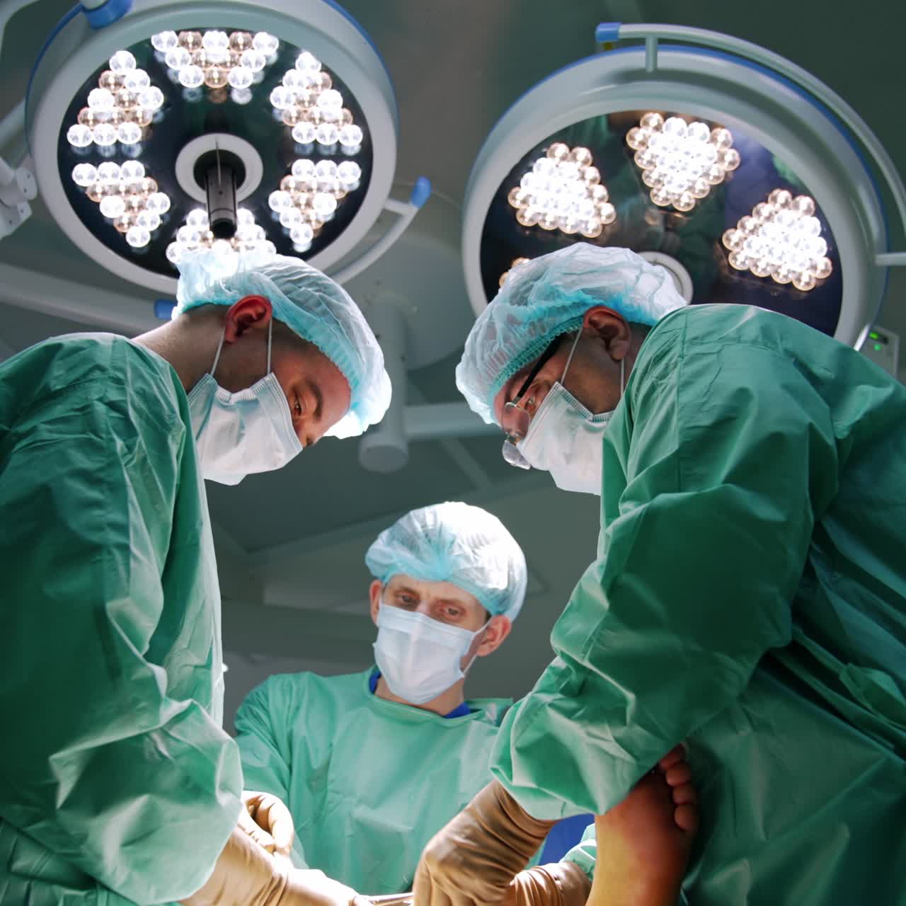 Team di chirurghi che operano il paziente. Medici eseguono un intervento chirurgico di guarigione traumatica al piede. Vista dal basso