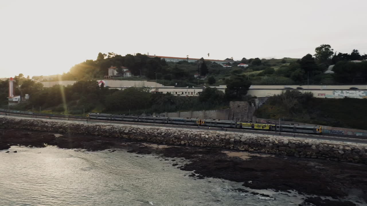 Aerial shot over Portuguese train on train tracks at sunset, Riverside Lisbon