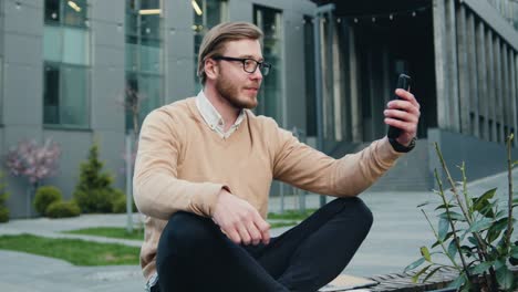portrait young businessman using a mobile phone and making conference chat near a modern office centre