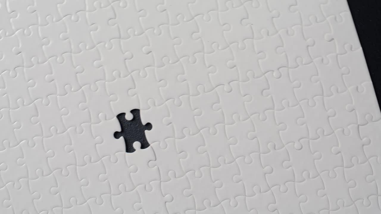 White puzzle lying dark table background surface closeup. Unfinished logic game