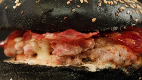 close-up of a black bun burger with bacon and cheese