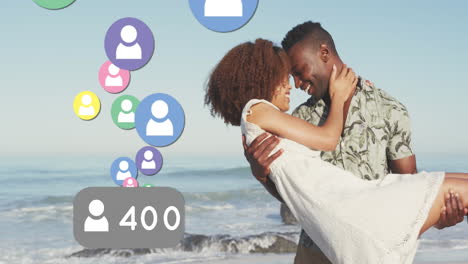 profile icons with increasing numbers against african american man picking up his wife on the beach