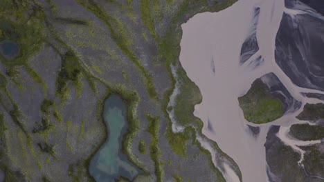 Aerial-top-down-shot-of-glacial-river-in-volcanic-landscape-of-Iceland-at-cloudy-day---flyover