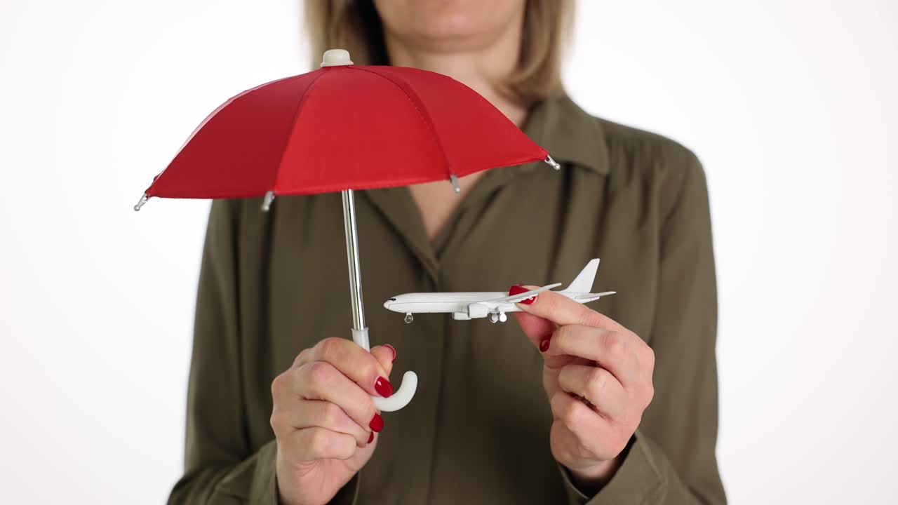 Donna tiene un ombrello rosso e un aereo giocattolo su sfondo bianco