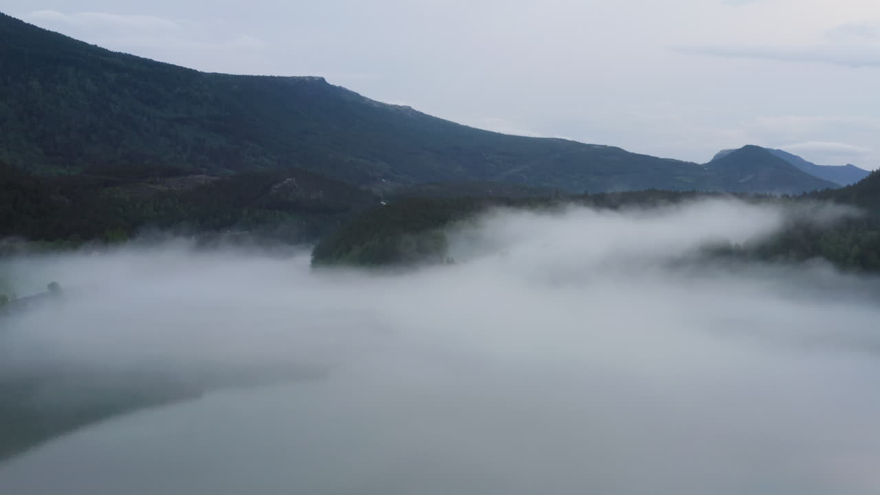 Flight over a foggy river. The mist is hanging low over the landscape creating a dark mystical mood over the whole scene.