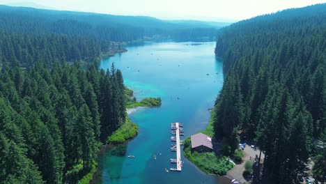 drone aerial landscape of crystal clear lake water reservoir with boat ramp wharf and cabin lodge hut in forest trees mountain region oregon usa america travel tourism nature