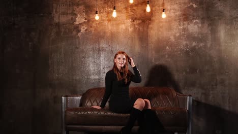 woman in black dress on a leather couch in an industrial setting