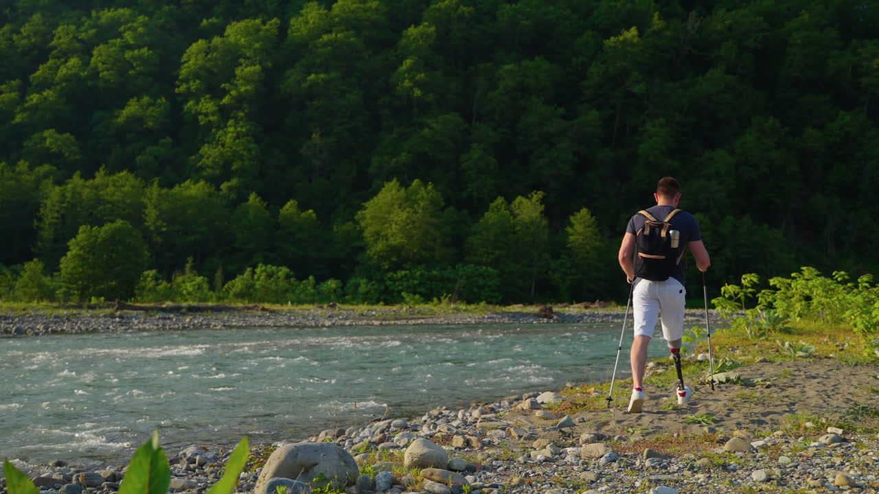 hombre con pierna protésica caminando por un río en un bosque