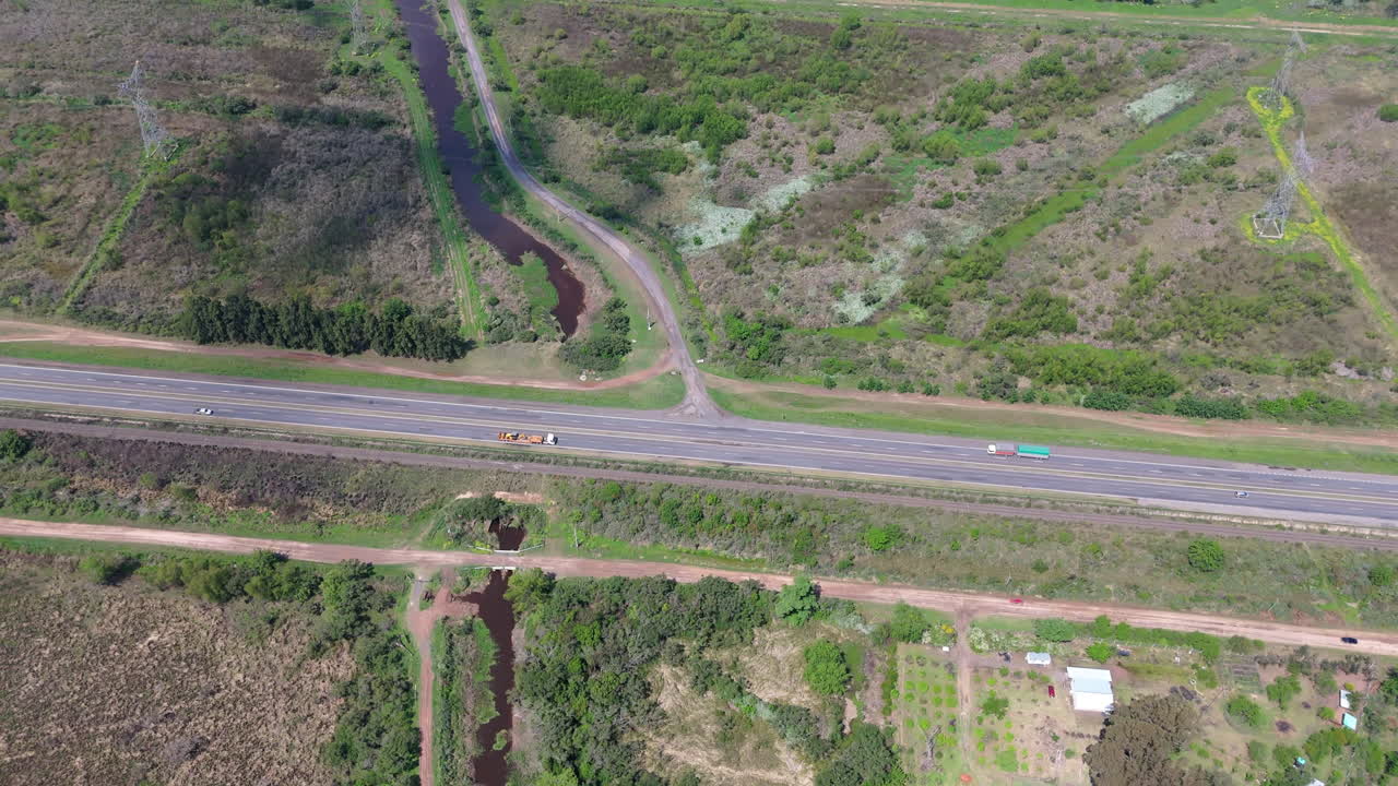 Aerial view of highway route with traffic cutting through a green rural landscape.