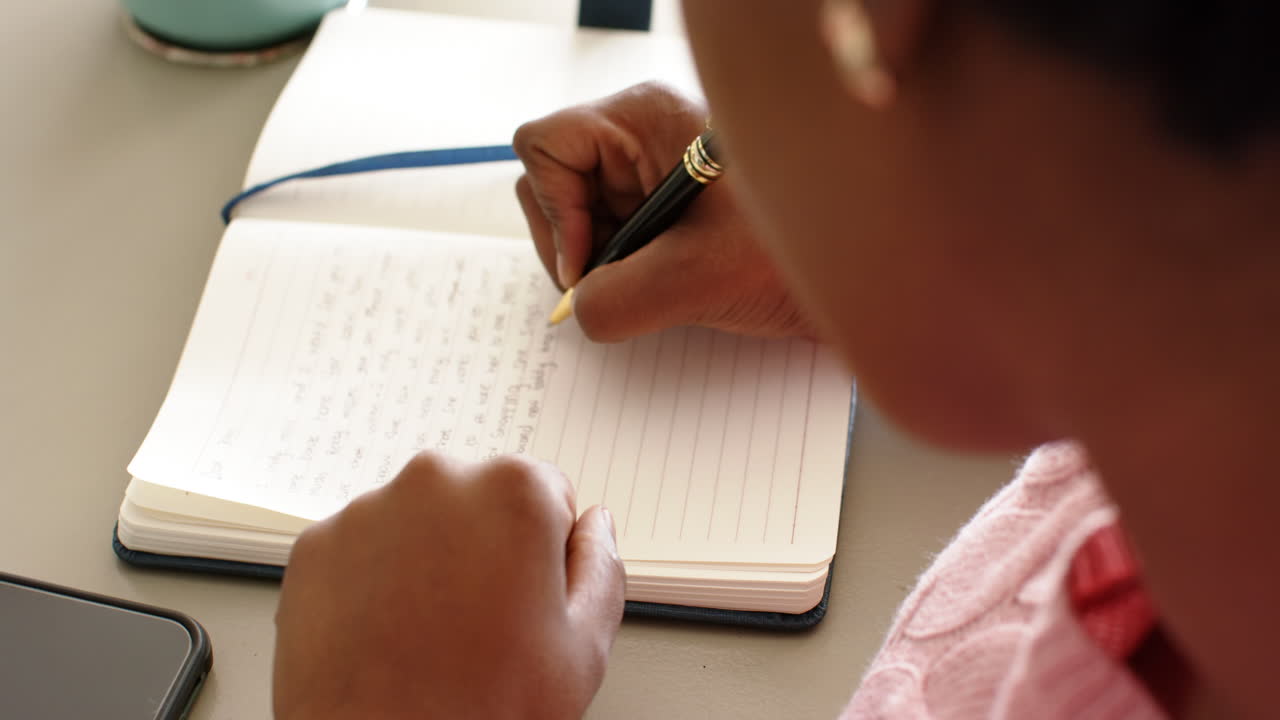 una mujer afroamericana está escribiendo en un cuaderno, fondo gris