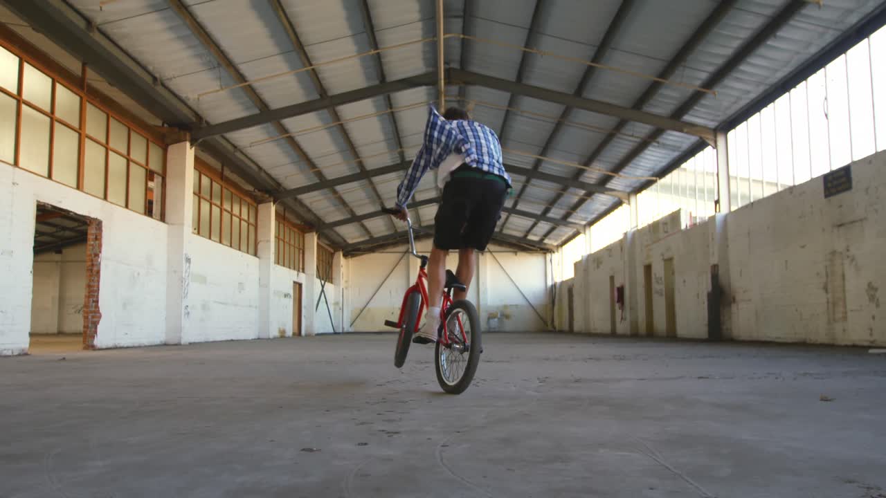 Ciclista BMX in un magazzino vuoto.