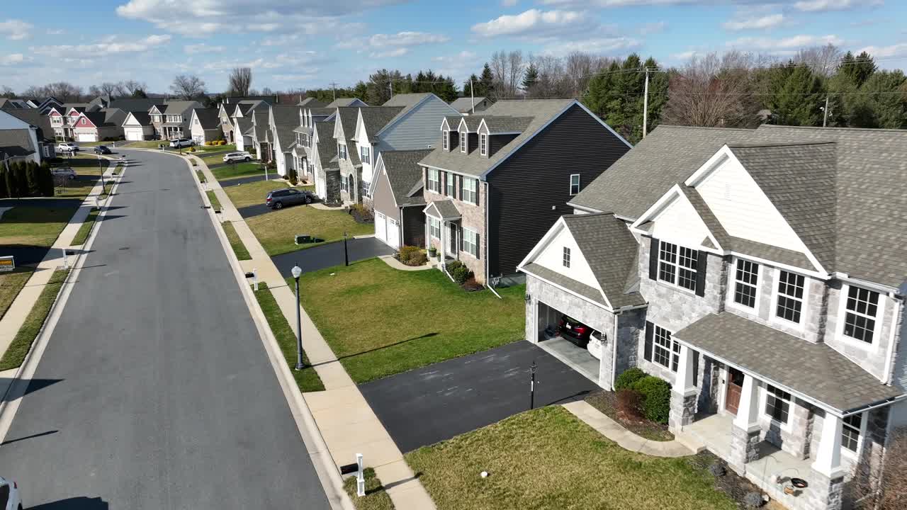 Angled aerial dolly above peaceful subdivision of large homes, sunny day