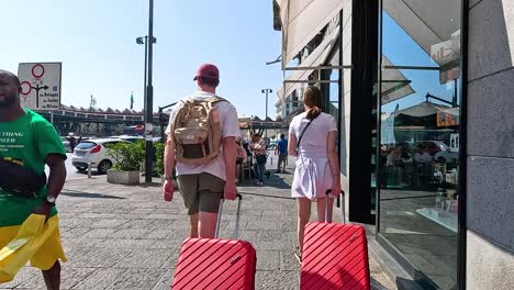 couple walking with luggage in sunny turin street