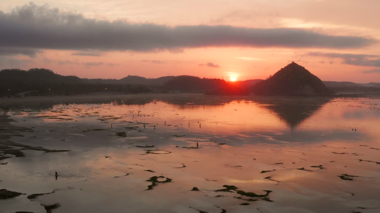 el arrecife seco de kuta lombok durante el amanecer, con gente local buscando comida y conchas marinas