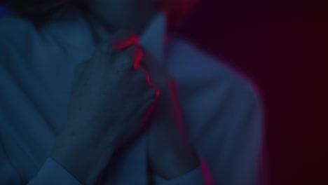 person adjusting tie in low light