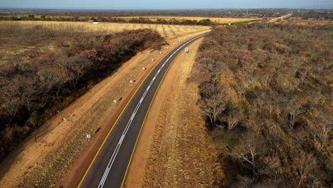 new road with safety signs cuts through dry landscape before farming town