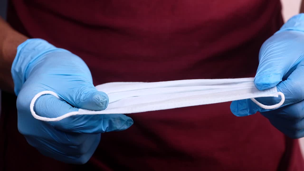persona con una máscara facial y guantes azules