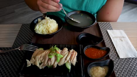 man dips spoon into asian style soup