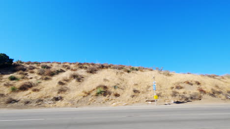 Driving-past-red-and-white-semitruck-on-mountain-highway-with-blue-sky