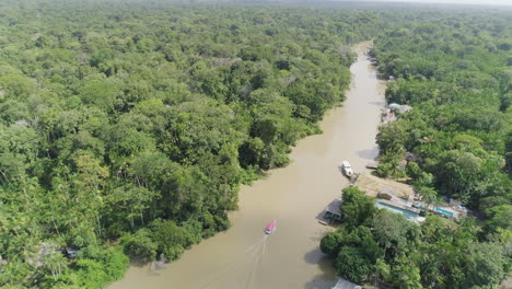 aerial shot following boat on amazonian river inside jungle