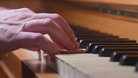una mano toca un acorde en un piano, de cerca