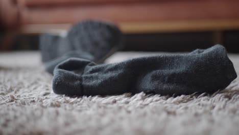 a single black sock lying on a grey carpet