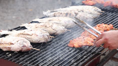 street vendor expertly grilling fish outdoors.