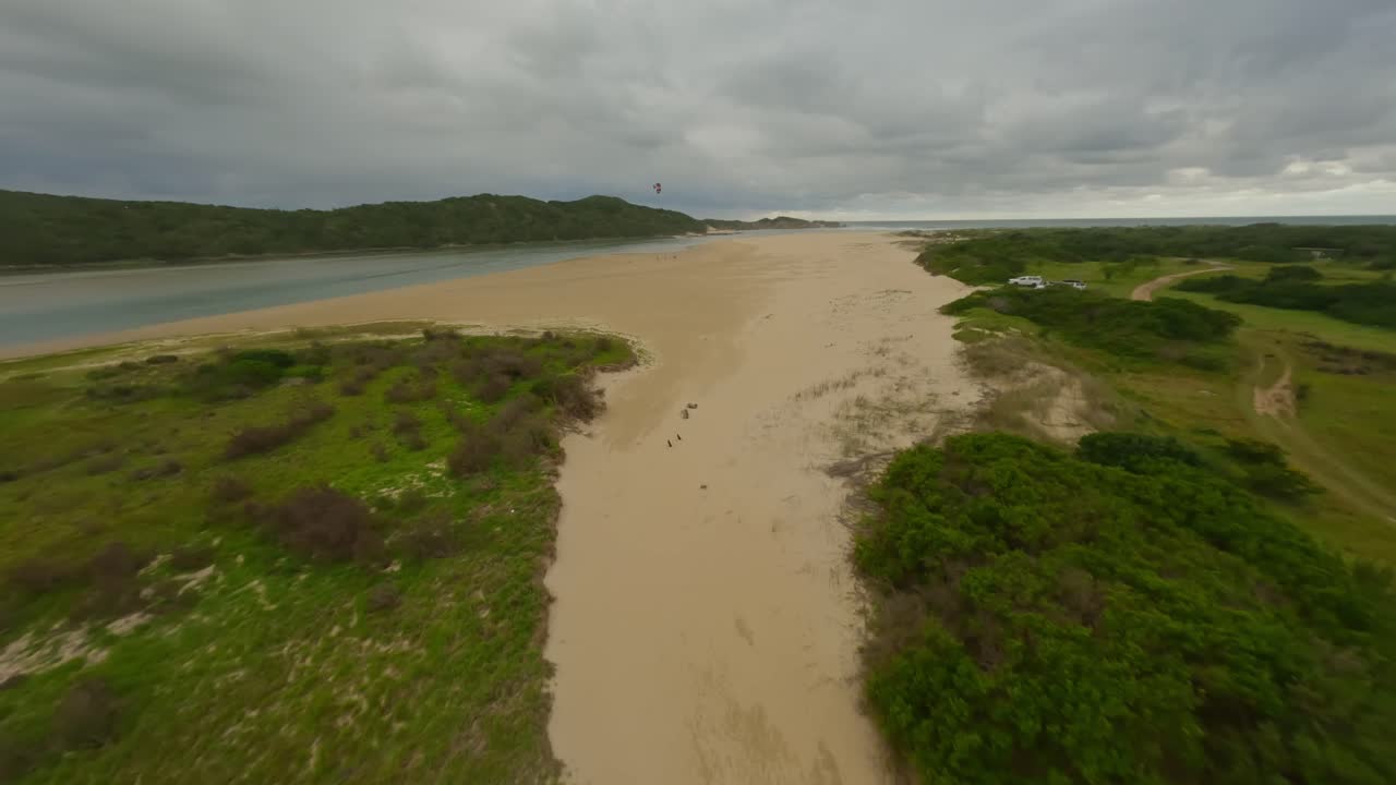 un dron revela a un kitesurfista volando su cometa en la desembocadura de un río en el cabo oriental