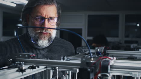 elderly engineer working with a machine in a lab