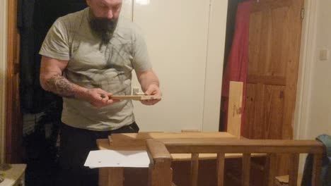 caucasian bearded male assembling flat pack pine furniture for home improvement