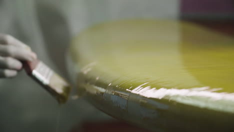 pintor aplicando una capa de pintura amarilla en una nueva tabla de surf
