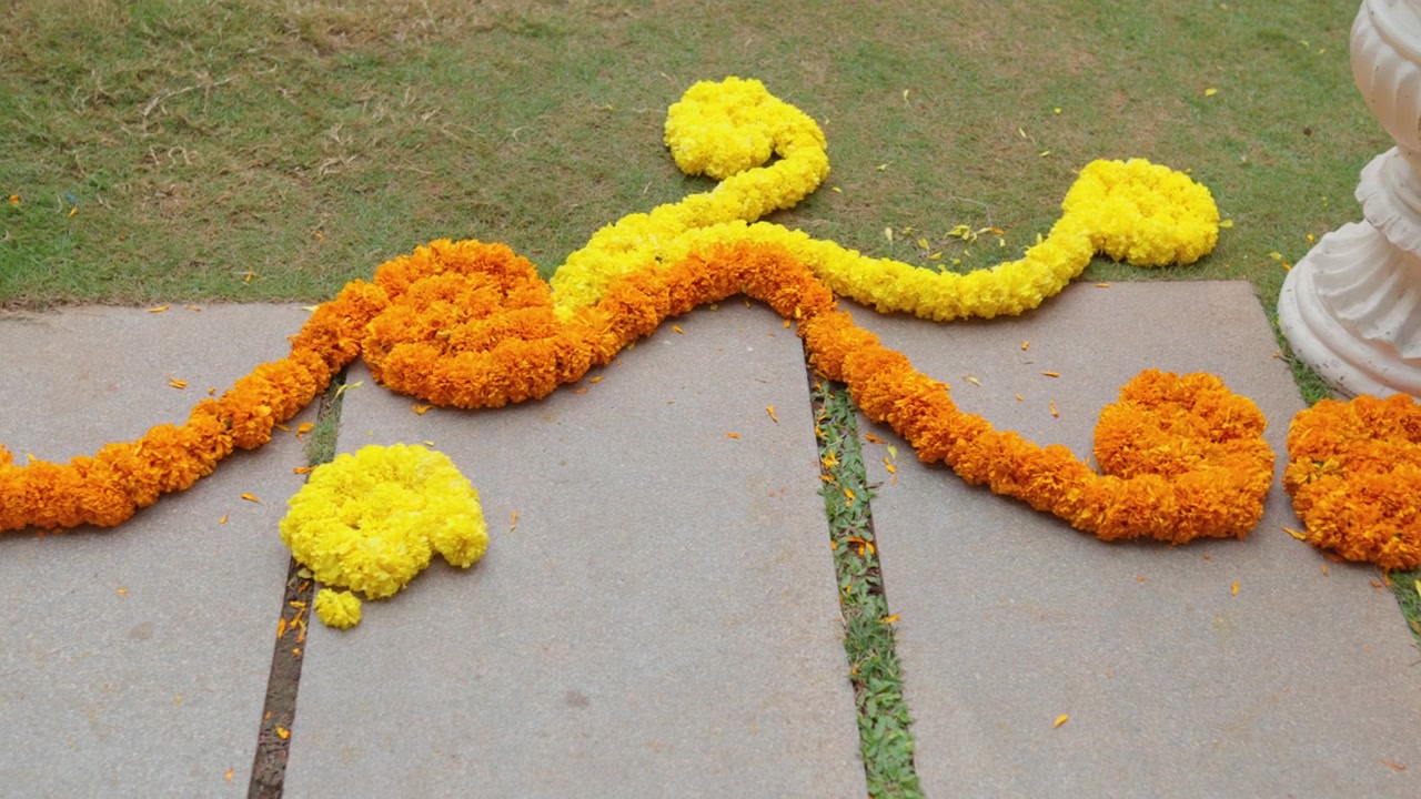Ghirlande di fiori di calendula disposte su un sentiero di pietra esterno per un festoso arredamento nuziale.