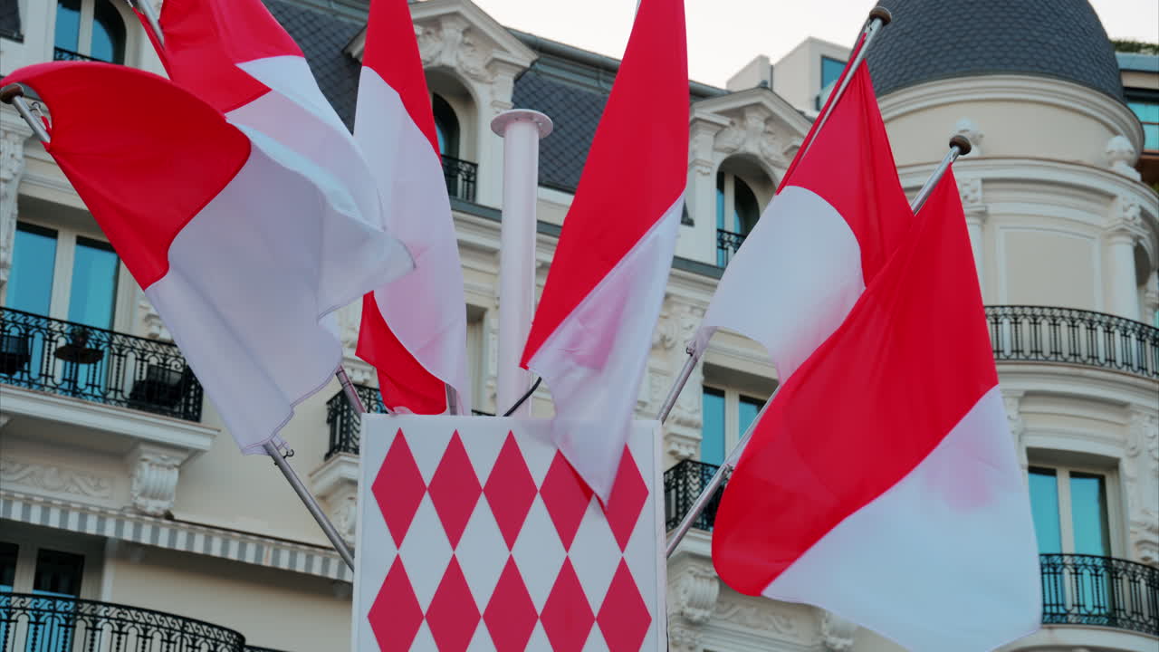 Monte Carlo, Monaco - October 24, 2024: The coat of arms of Monaco and multiple flags waving in front of the Hotel de Paris