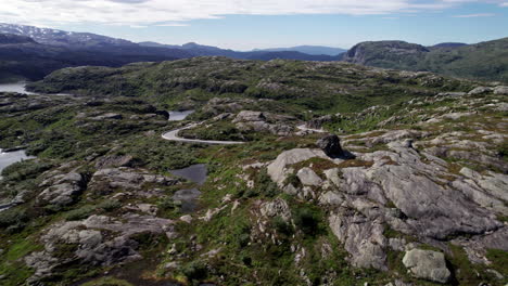 aerial shot, over a series of small lakes, surrounded by a rocky, moss covered landscape in norway