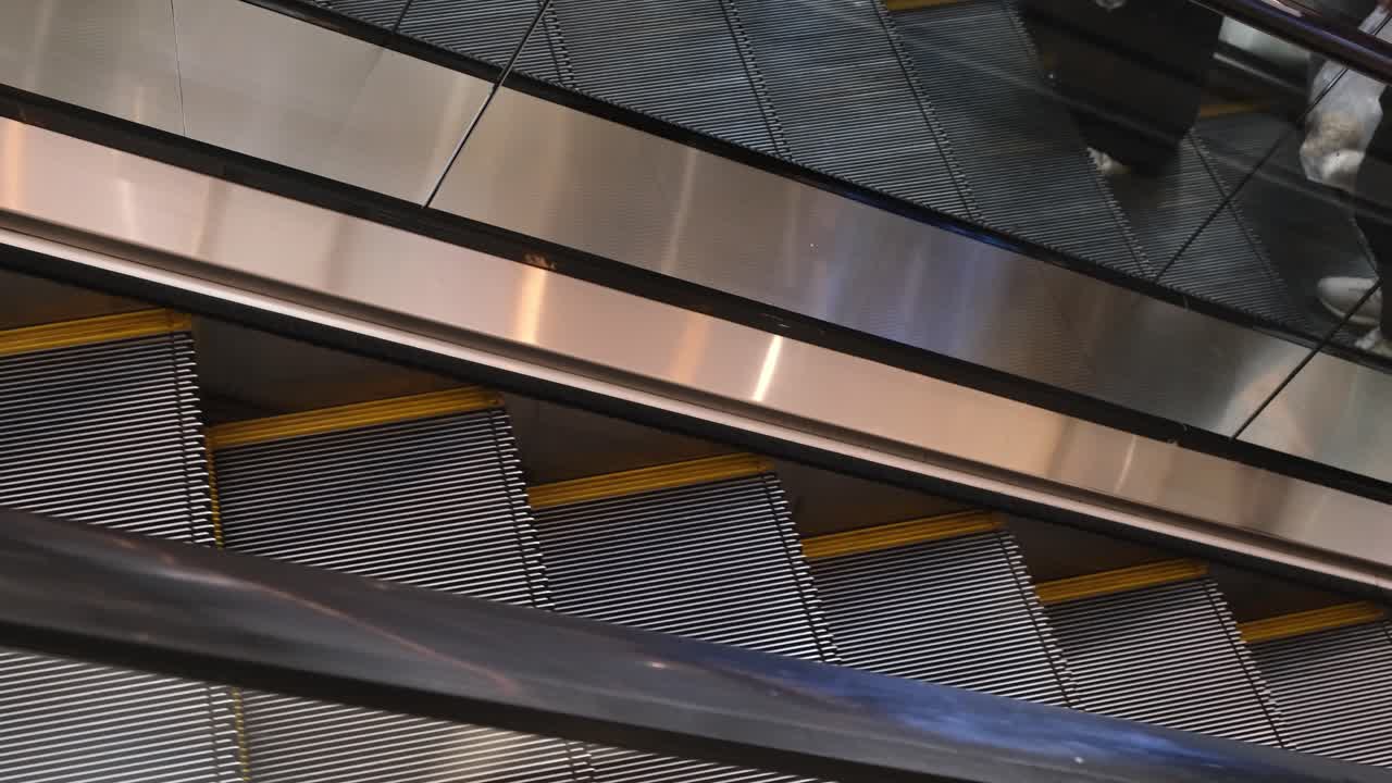 Commuters and shoppers going up and down the escalators inside a shopping mall in a major tourist area in Southeast Asia.