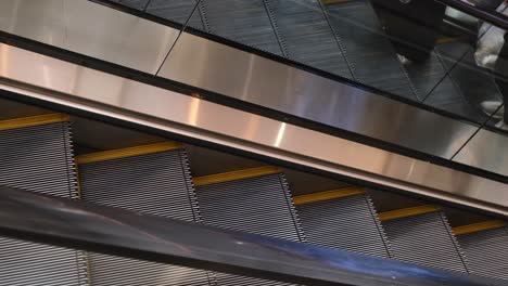 commuters and shoppers going up and down the escalators inside a shopping mall in a major tourist area in southeast asia.